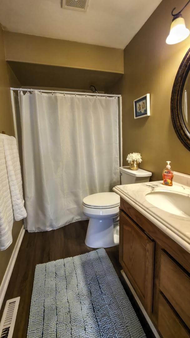 full bathroom with visible vents, curtained shower, toilet, wood finished floors, and vanity