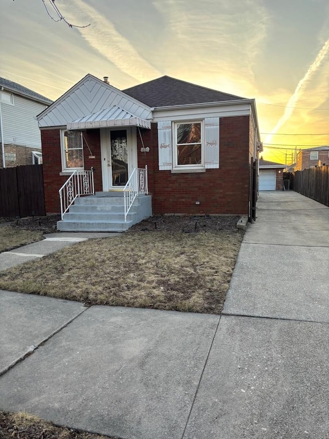 bungalow-style house with an outbuilding, fence, and brick siding