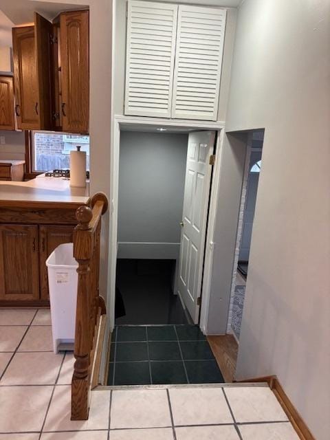 kitchen featuring light tile patterned flooring, baseboards, and brown cabinets