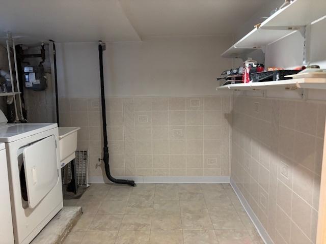 laundry room featuring laundry area, washing machine and dryer, and tile walls