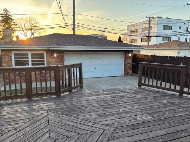 wooden terrace featuring an outbuilding, an attached garage, and fence