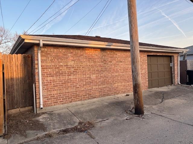 view of side of home featuring a garage, fence, and brick siding