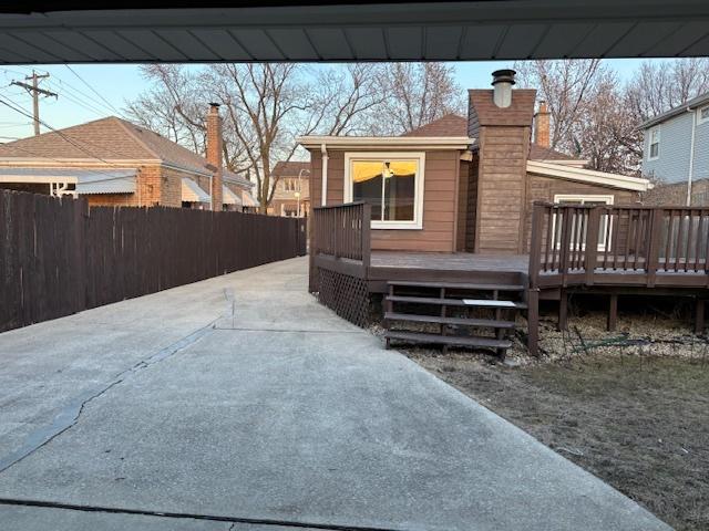 view of side of home with a wooden deck, a chimney, and fence