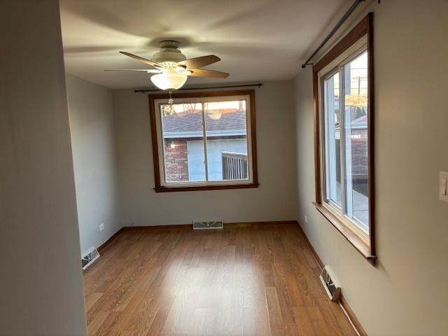 unfurnished room with light wood finished floors, visible vents, baseboards, and ceiling fan