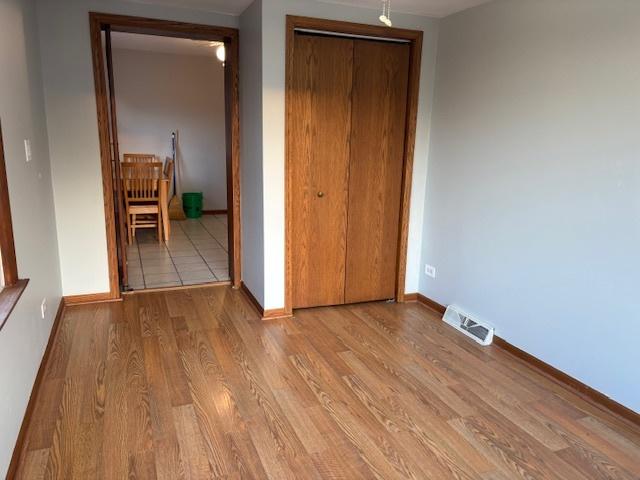 unfurnished bedroom featuring a closet, visible vents, baseboards, and wood finished floors