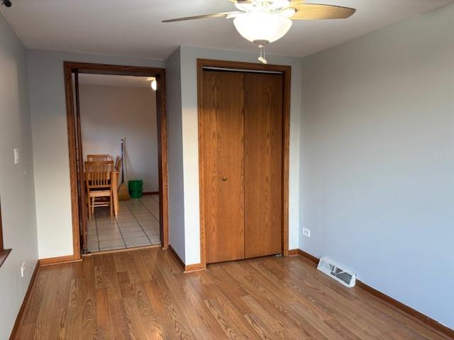 unfurnished bedroom featuring visible vents, a ceiling fan, wood finished floors, a closet, and baseboards