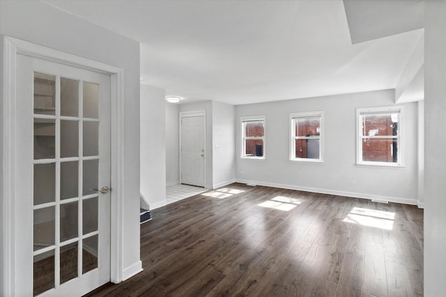 unfurnished room featuring baseboards and dark wood-type flooring