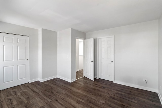 unfurnished bedroom with baseboards and dark wood-type flooring