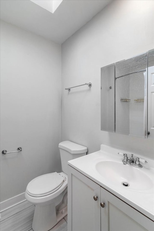 bathroom featuring toilet, vanity, and baseboards