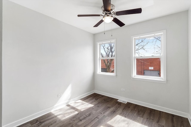 empty room with dark wood finished floors, visible vents, ceiling fan, and baseboards