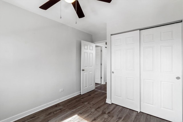 unfurnished bedroom featuring a closet, a ceiling fan, dark wood-type flooring, and baseboards