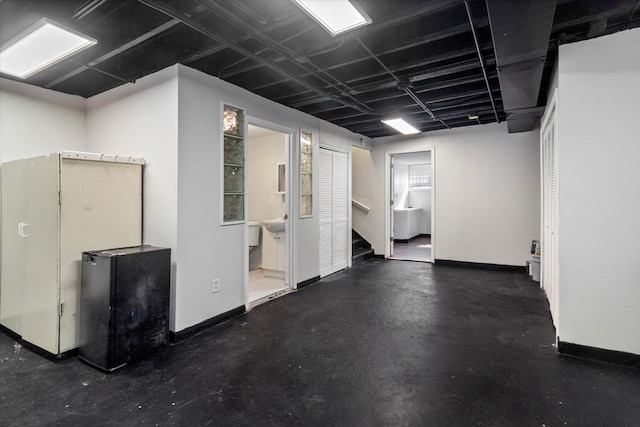 finished basement featuring stairway, baseboards, and freestanding refrigerator