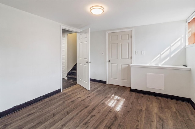 spare room featuring stairs, baseboards, and wood finished floors