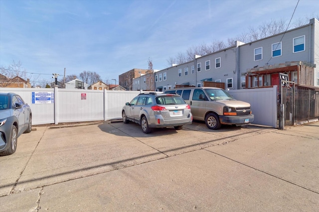 uncovered parking lot featuring a residential view and fence