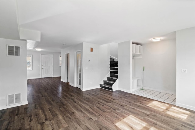 unfurnished living room featuring stairs, wood finished floors, and visible vents