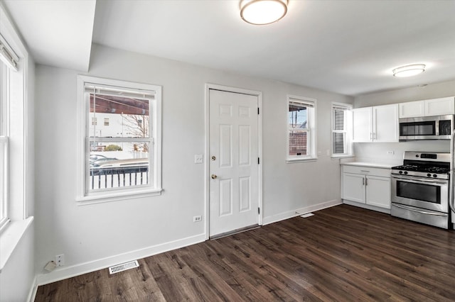 kitchen with visible vents, baseboards, appliances with stainless steel finishes, white cabinets, and dark wood-style flooring