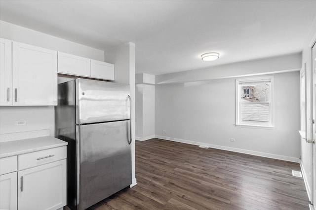 kitchen with white cabinetry, dark wood-type flooring, baseboards, and freestanding refrigerator