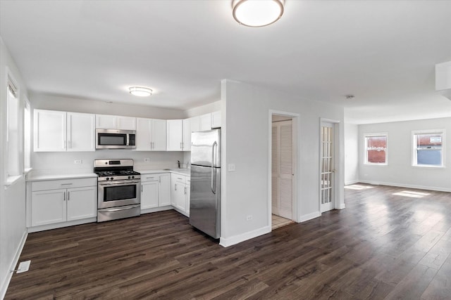 kitchen featuring baseboards, light countertops, appliances with stainless steel finishes, dark wood-style floors, and white cabinetry