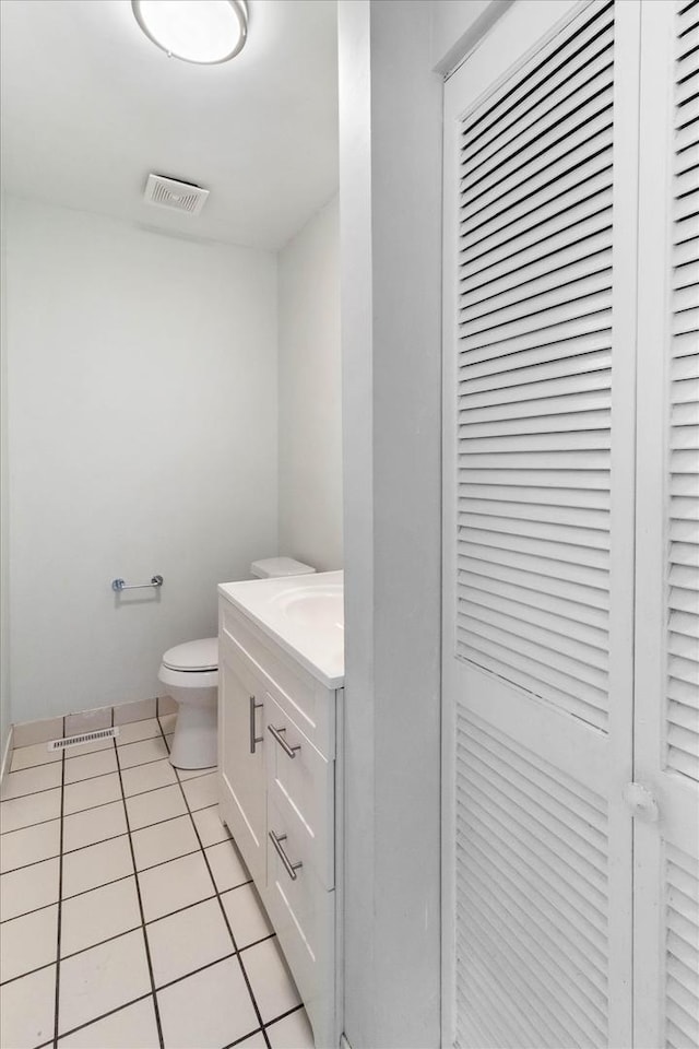 half bath featuring tile patterned floors, visible vents, toilet, and vanity