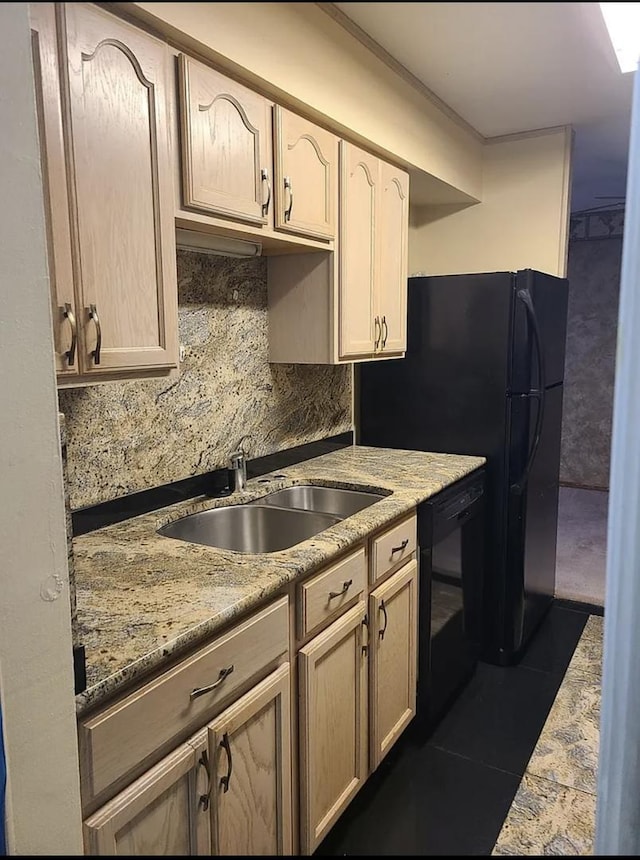 kitchen with dark tile patterned floors, a sink, light stone counters, black dishwasher, and decorative backsplash