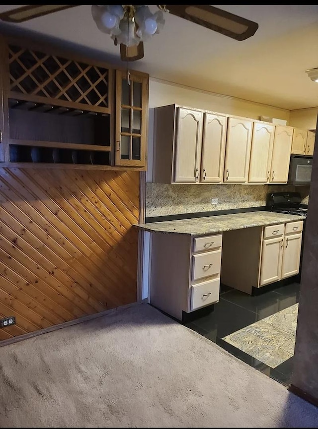 kitchen featuring backsplash, glass insert cabinets, black microwave, ceiling fan, and wood walls