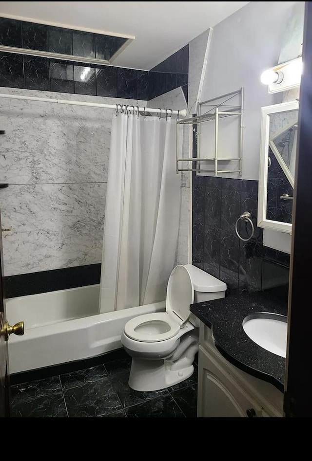 full bath featuring vanity, shower / bathtub combination with curtain, tile walls, toilet, and marble finish floor