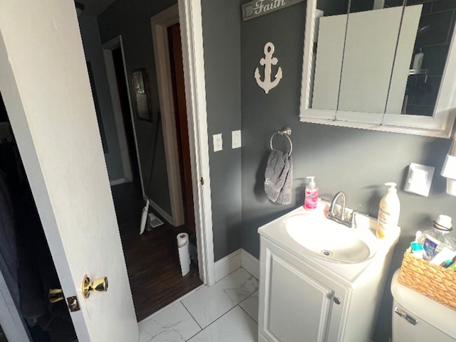 half bath featuring vanity, toilet, baseboards, and marble finish floor