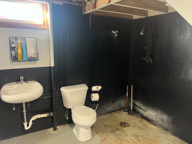 bathroom with unfinished concrete floors, toilet, and a sink