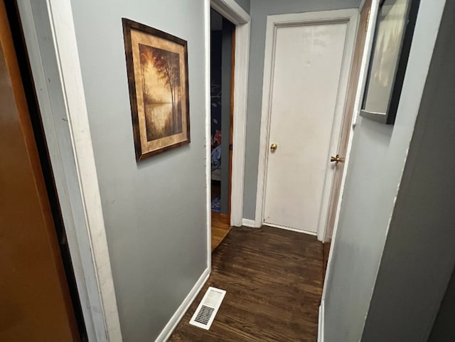 hallway with visible vents, baseboards, and dark wood-style floors