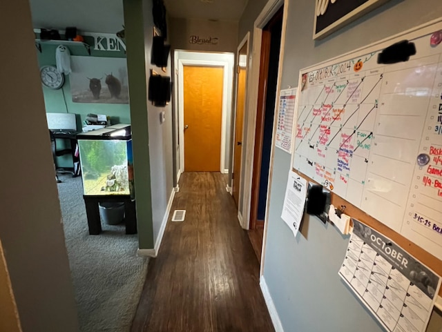 corridor featuring visible vents, baseboards, and dark wood-style flooring