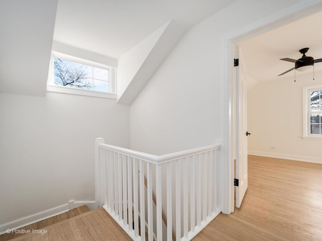 hallway with wood finished floors, an upstairs landing, and baseboards