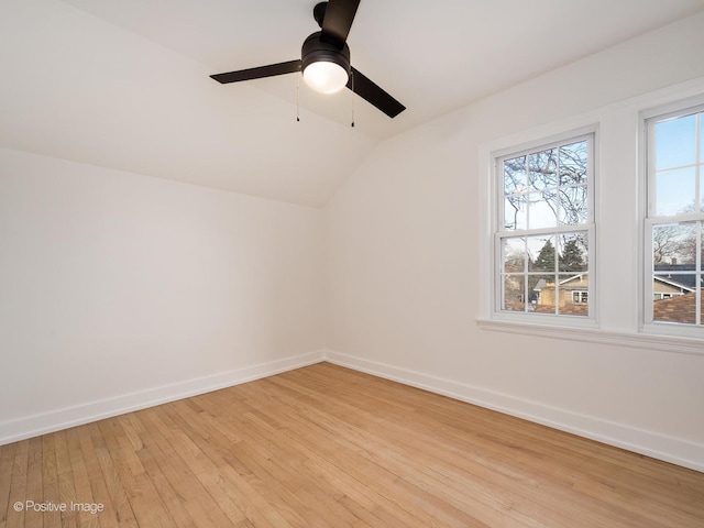 spare room with ceiling fan, baseboards, light wood-type flooring, and lofted ceiling