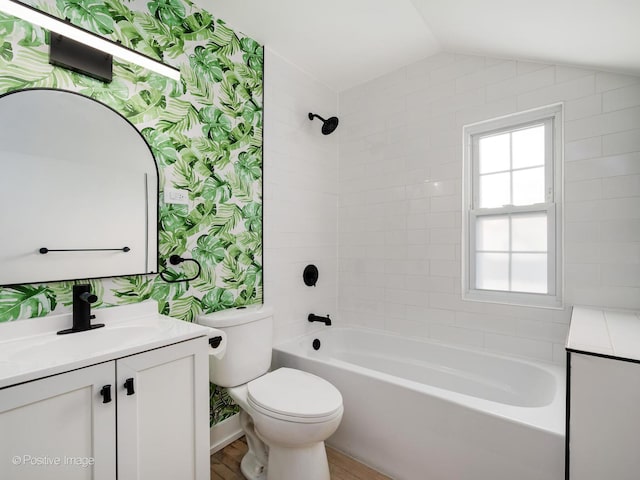 bathroom with wallpapered walls, vaulted ceiling, toilet, and vanity