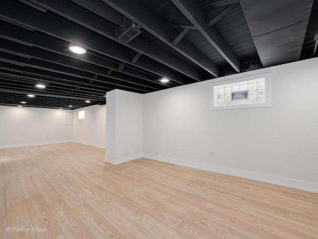 below grade area featuring wood finished floors, visible vents, and baseboards