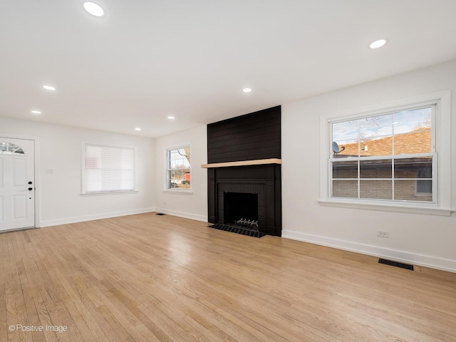 unfurnished living room with baseboards, visible vents, light wood finished floors, recessed lighting, and a large fireplace