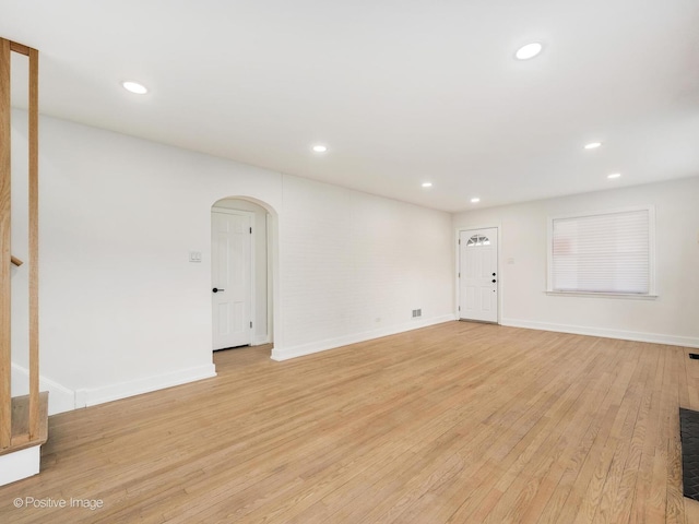 unfurnished living room with arched walkways, recessed lighting, and light wood-type flooring