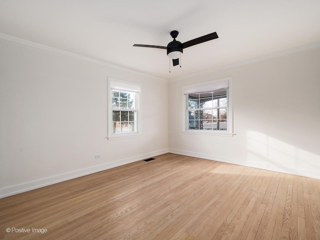 empty room featuring hardwood / wood-style floors, visible vents, a wealth of natural light, and ornamental molding