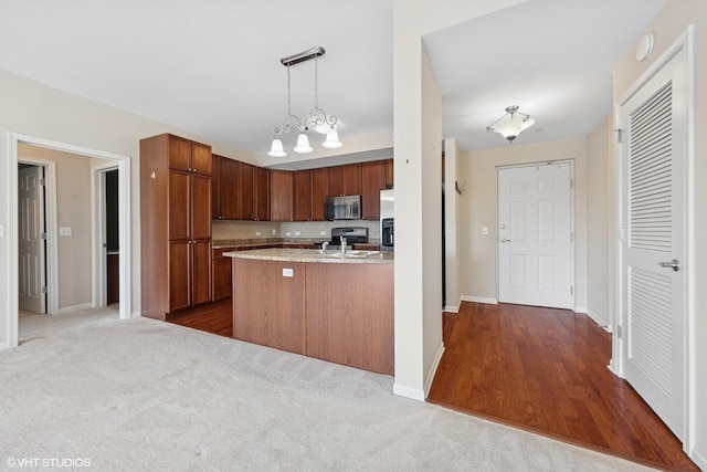 kitchen featuring baseboards, decorative backsplash, appliances with stainless steel finishes, pendant lighting, and dark carpet