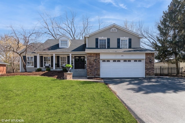 traditional home featuring driveway, fence, a front yard, a garage, and brick siding