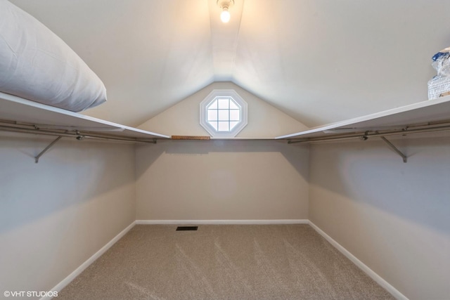 spacious closet with vaulted ceiling, visible vents, and carpet floors