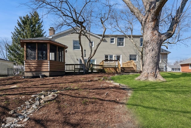 back of house with a deck, a yard, a sunroom, and a chimney