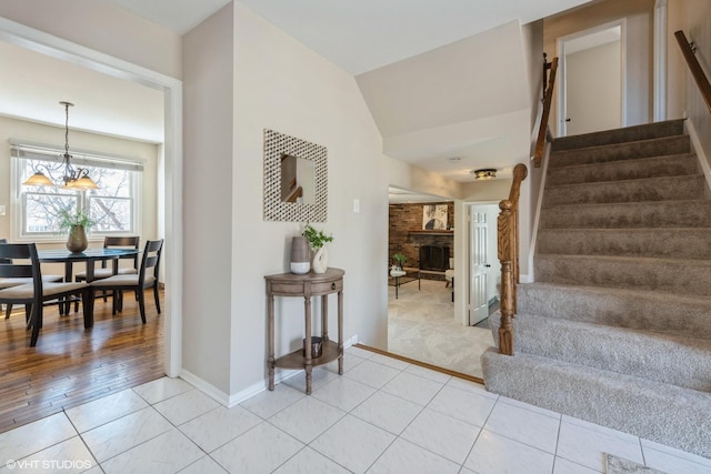 stairway featuring tile patterned flooring, lofted ceiling, carpet, and a fireplace