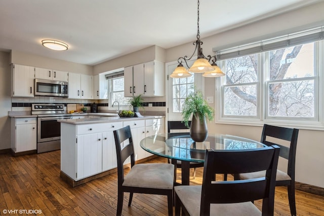 kitchen with backsplash, white cabinets, appliances with stainless steel finishes, and dark wood-style flooring