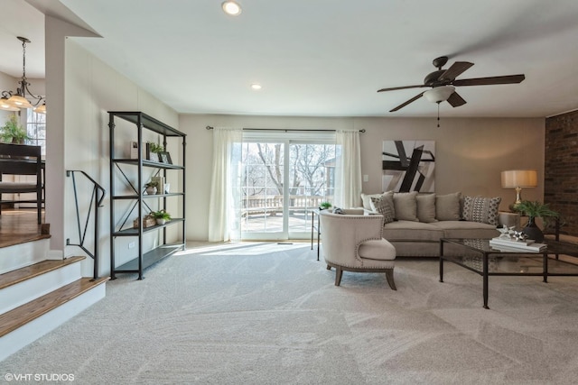 carpeted living area featuring recessed lighting, stairs, and ceiling fan with notable chandelier