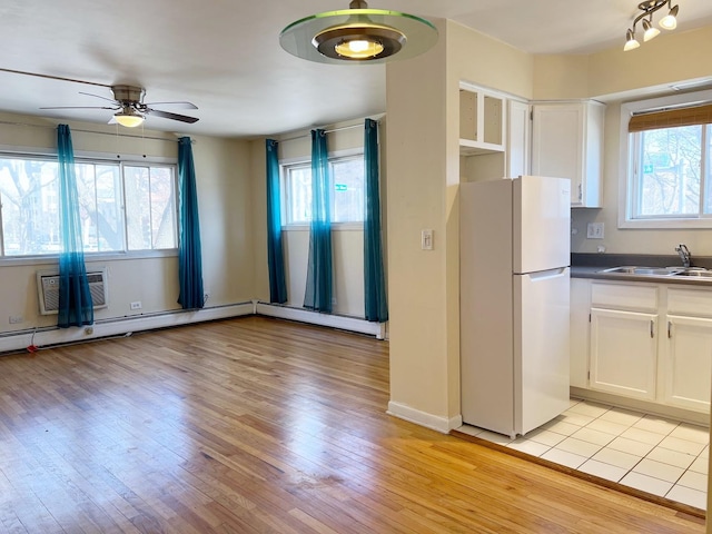 kitchen with light wood finished floors, white cabinetry, freestanding refrigerator, and a sink