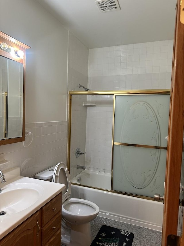 full bathroom with vanity, visible vents, bath / shower combo with glass door, tile walls, and toilet