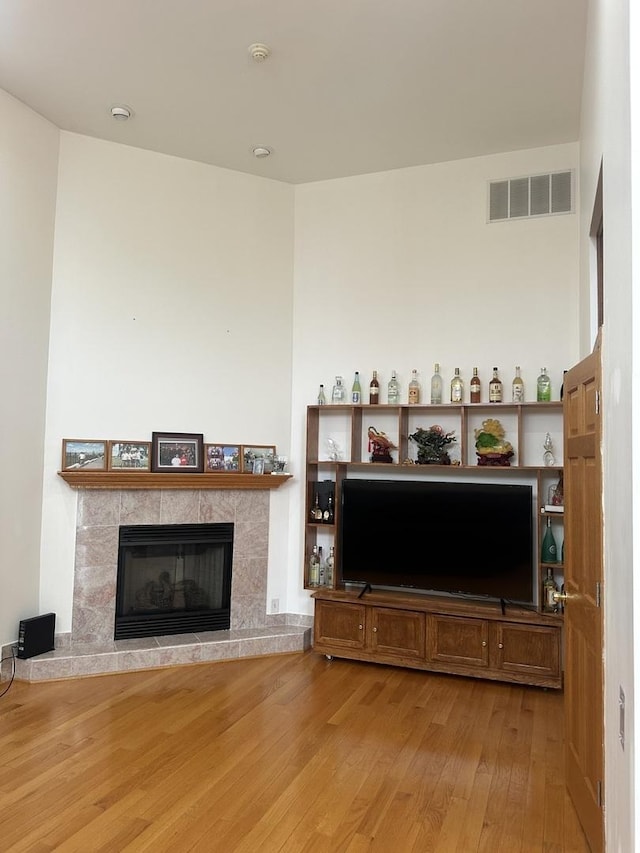 living area featuring visible vents, a tile fireplace, and wood-type flooring