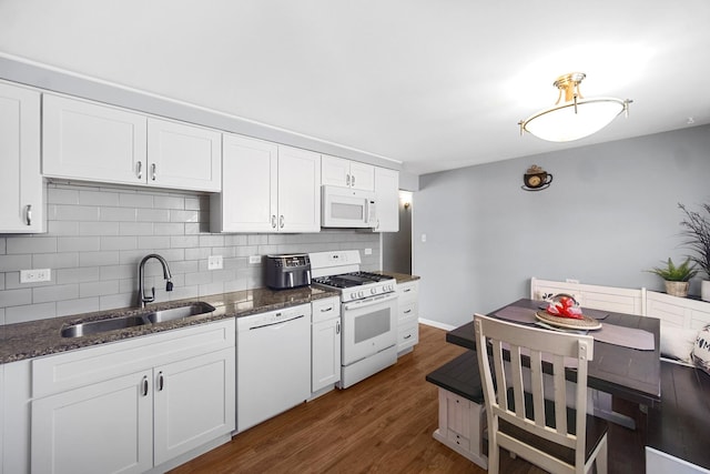 kitchen featuring white appliances, dark wood finished floors, a sink, white cabinetry, and tasteful backsplash