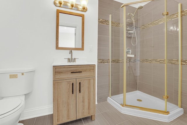 bathroom with baseboards, vanity, toilet, and a shower stall