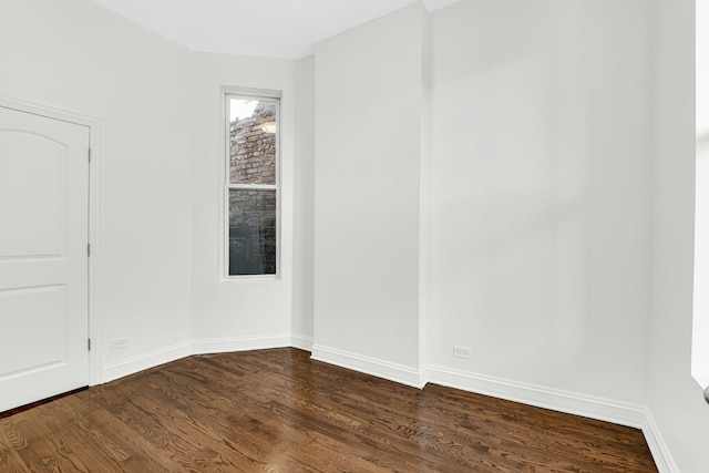 empty room featuring dark wood-style floors and baseboards